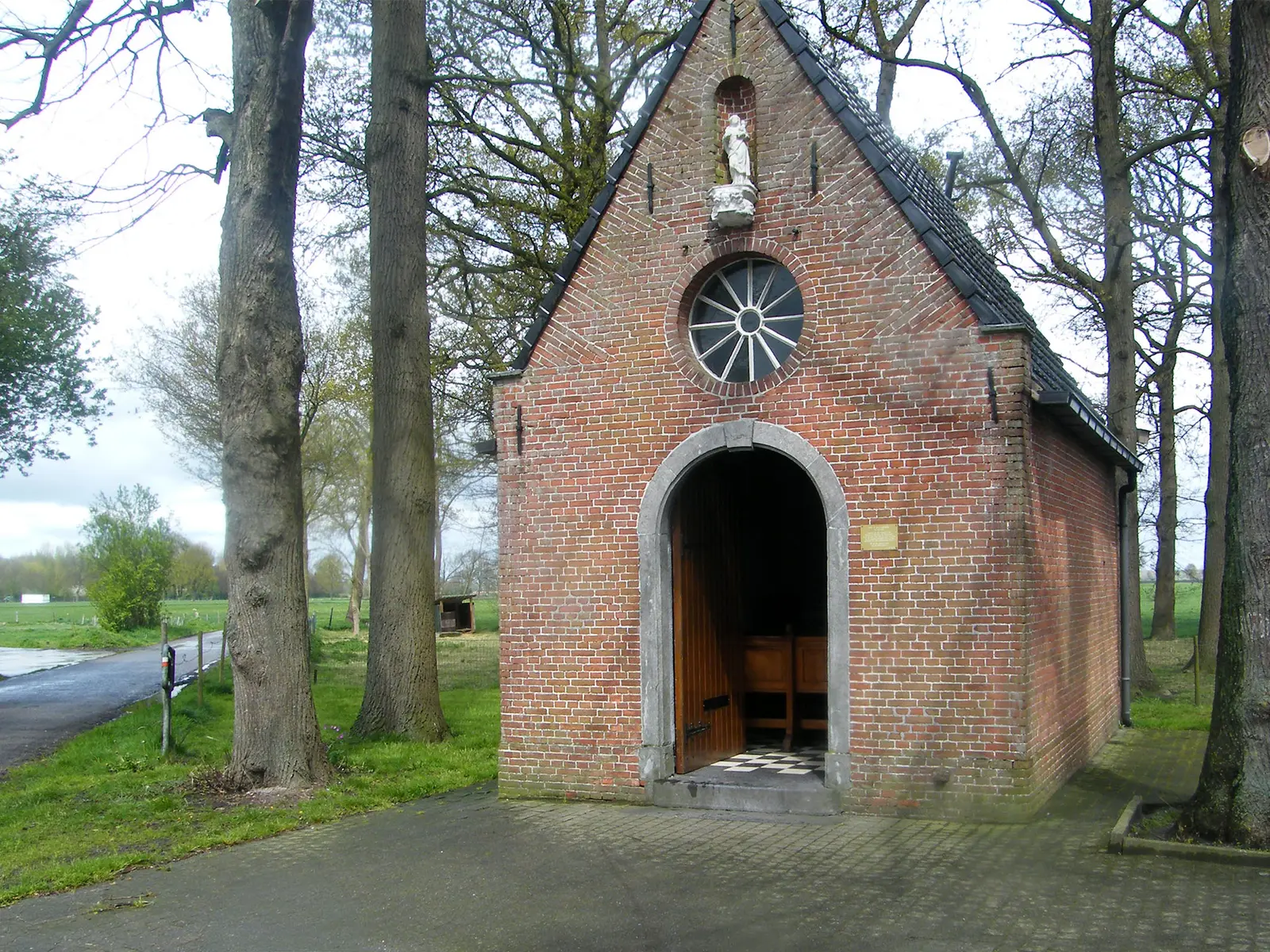 Kleine bakstenen kapel tussen bomen in het buitengebied